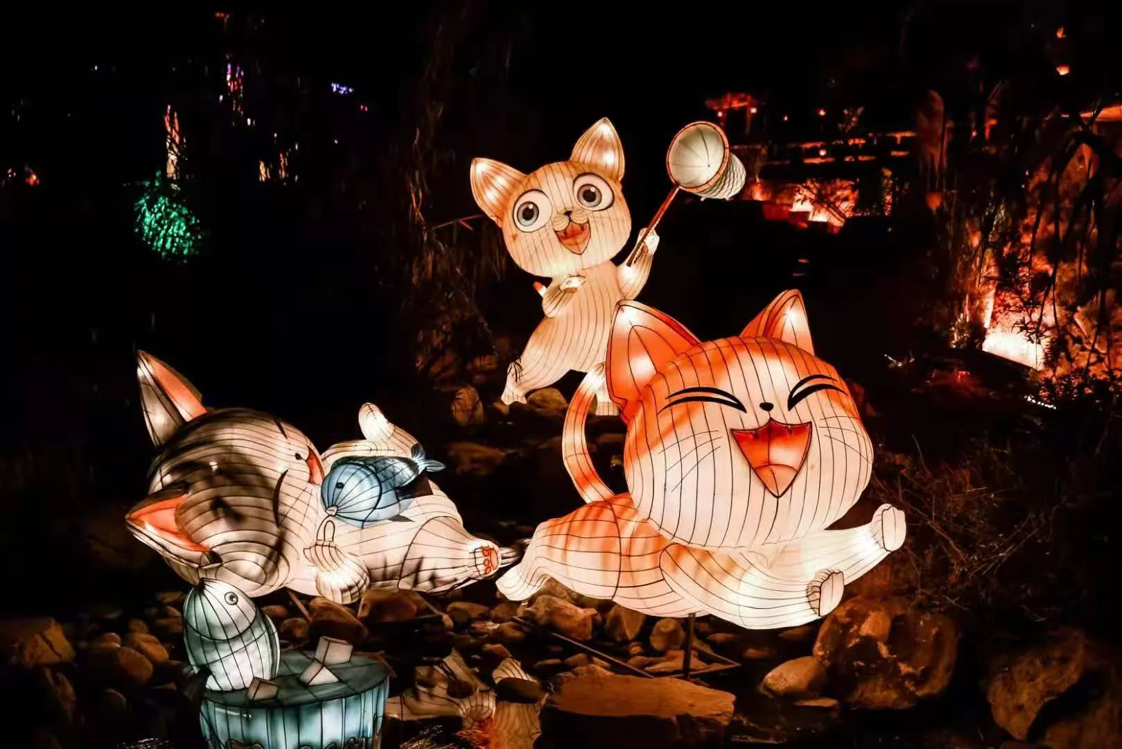 Playful Miss Cat lantern characters beside a creek at night