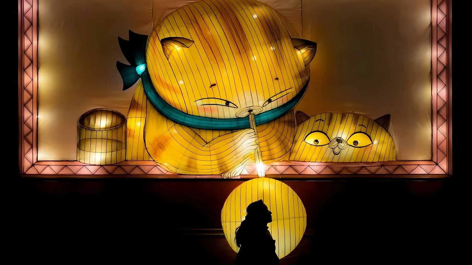 Backlit Miss Cat lantern wall with a visitor silhouette in Hong Kong