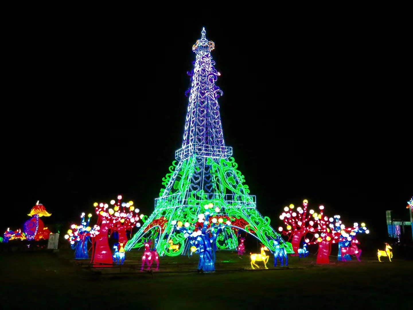 Eiffel-inspired tower lantern installation glowing with trees around it