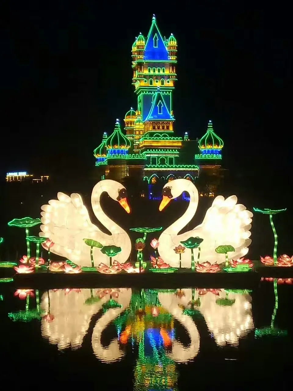 Illuminated swans and castle reflected on water at the Sochi lantern exhibition