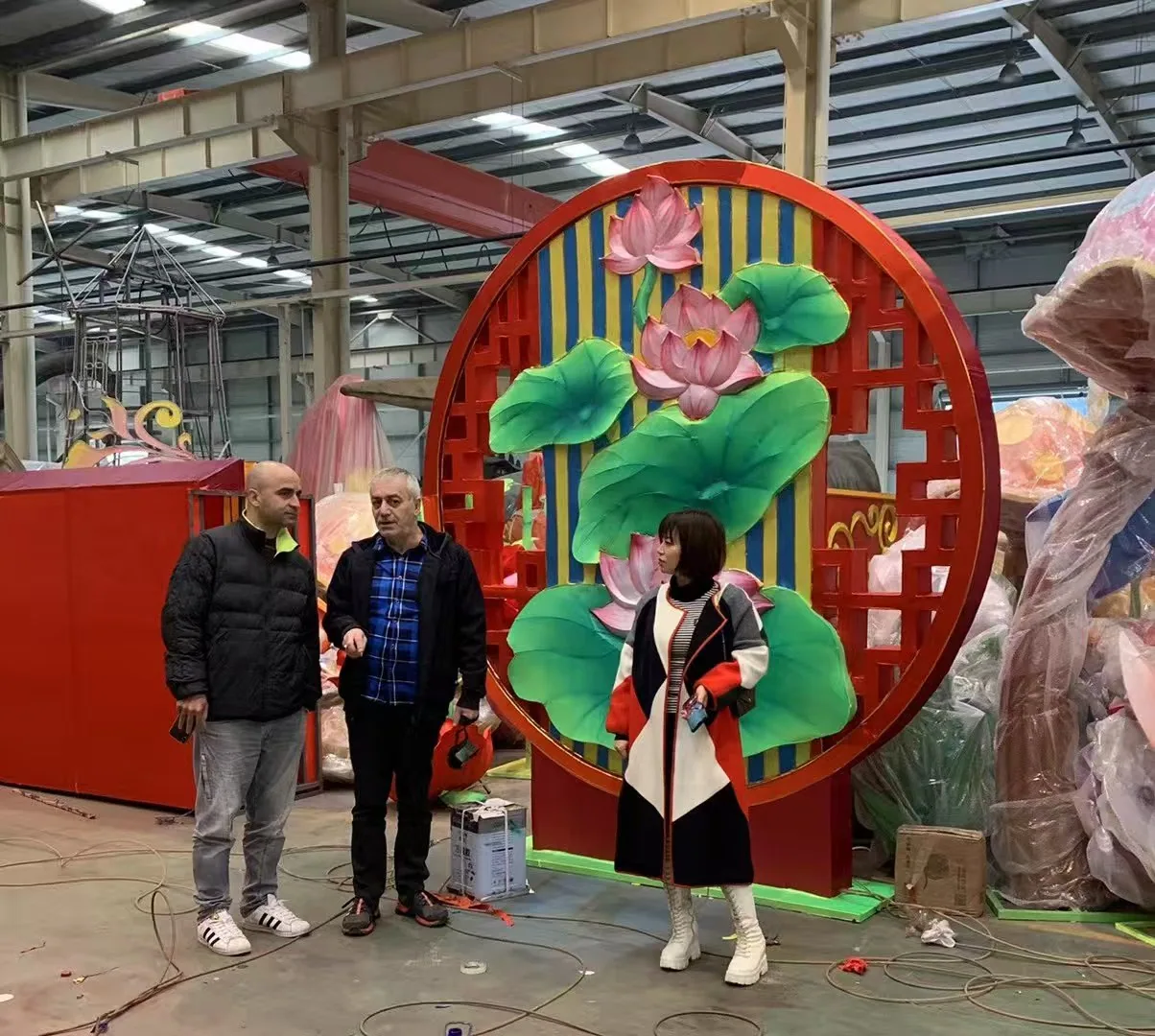 Client inspecting lotus themed lantern structures inside the Shilong workshop